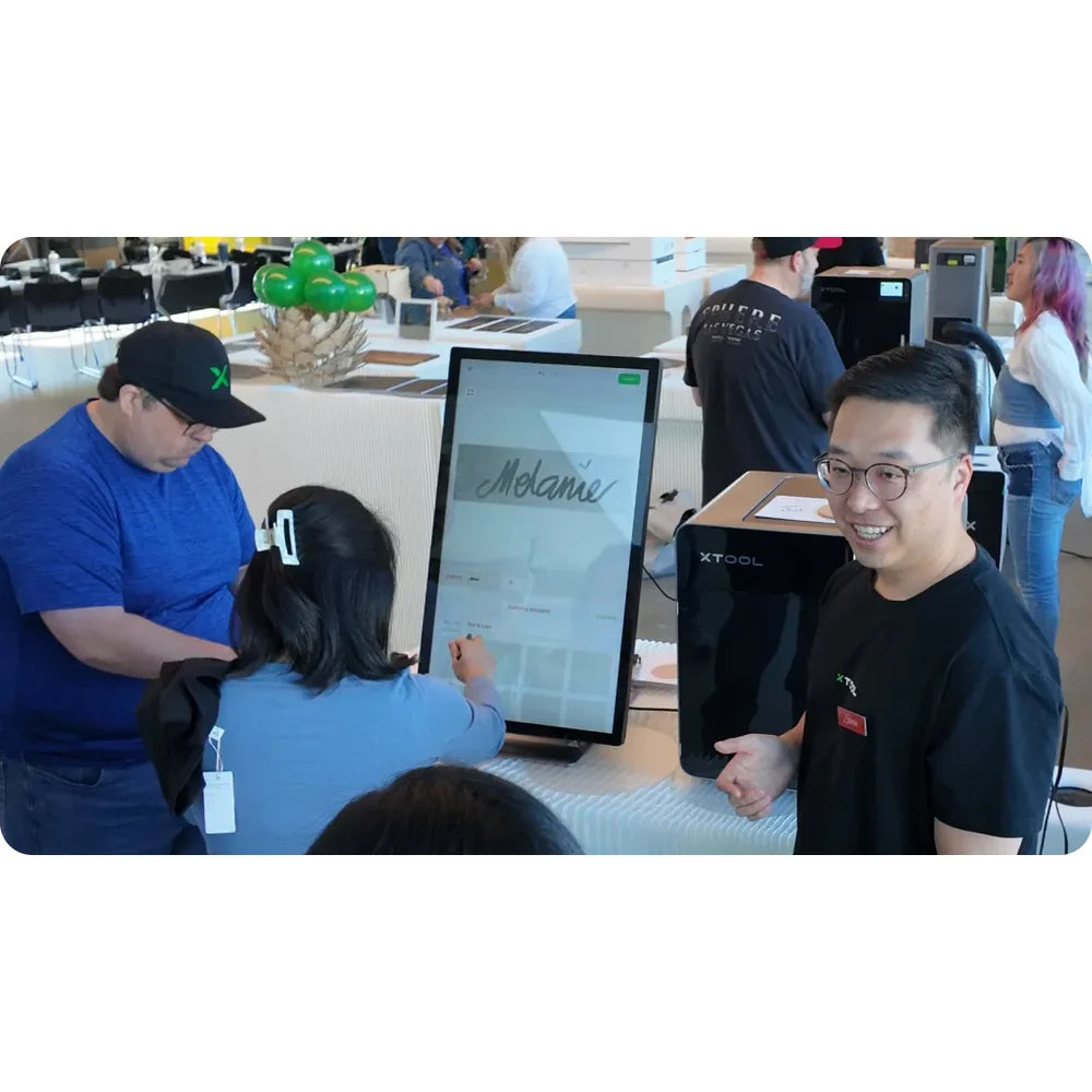 Customers prepare a name design near xTool F2 Ultra Color Engraving hardware at an event