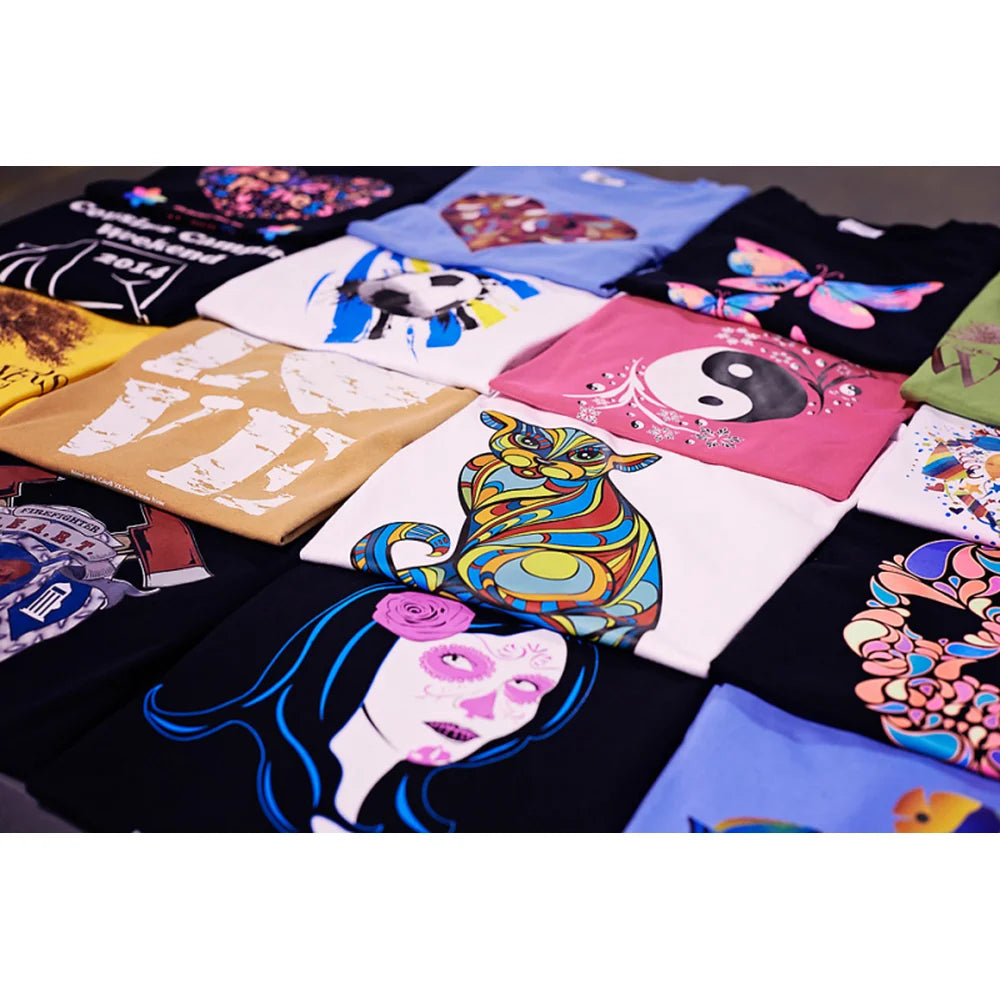 Assorted colored t-shirts arranged flat with vivid printed designs made using the IColor Textile Sample Paper Kit transfers