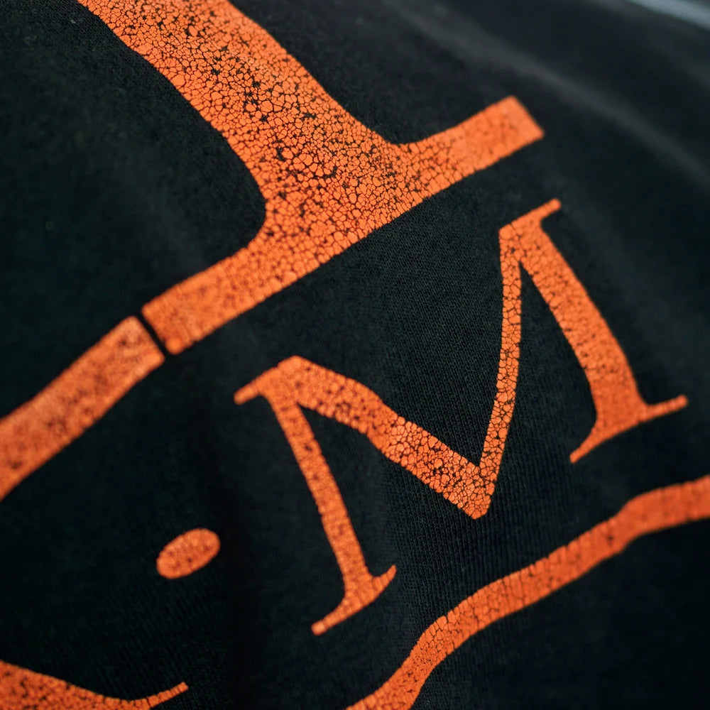 Close view of a distressed orange transfer on black cotton pressed with a Geo Knight DK14S 12x14 Heat Press Machine