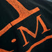 Close view of a distressed orange transfer on black cotton pressed with a Geo Knight DK14S 12x14 Heat Press Machine