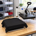 Black tee laid on the lower platen of a Geo Knight DK14S Transfer Press Machine in a shop with stocked shirt shelves