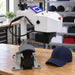 Geo Knight DC7AP Swing Away Heat Press Machine on a wooden print shop bench beside a navy cap and stocked shelves