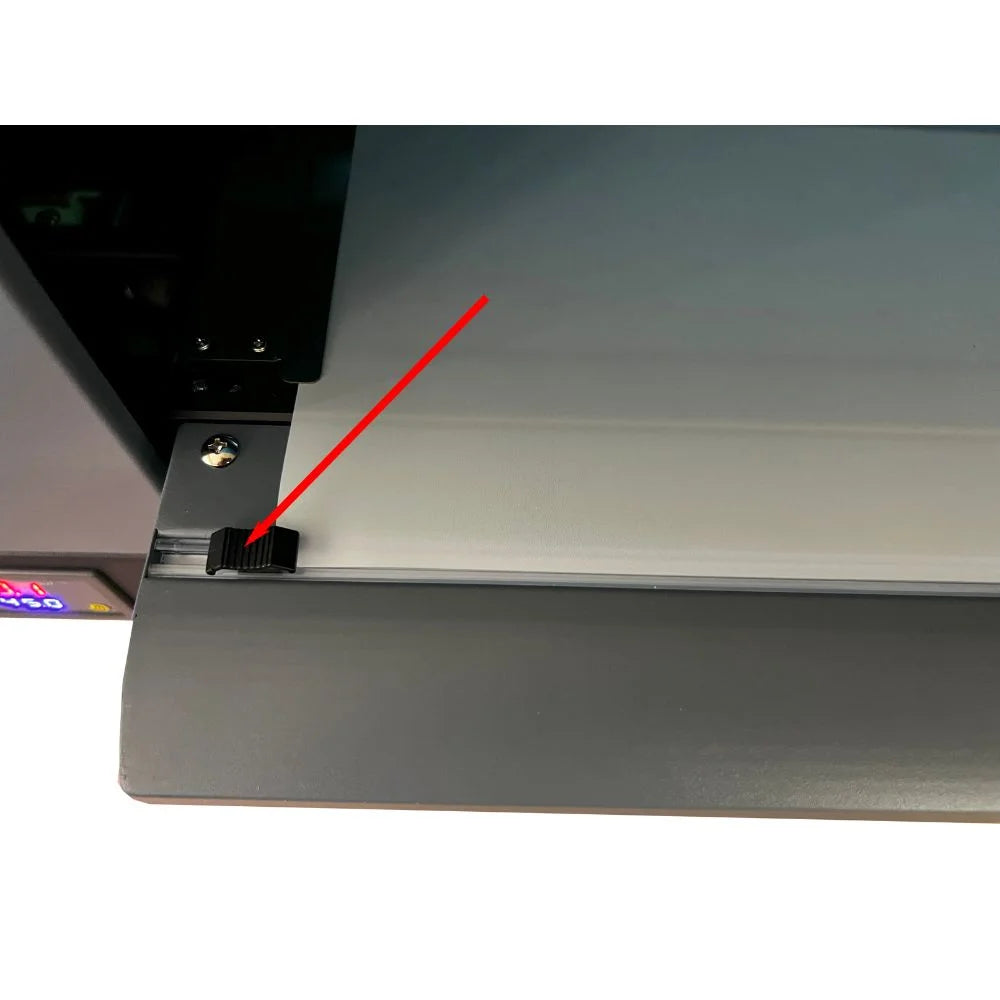 Detail of the uninet icolor 1200 film exit edge with a red arrow marking the black media guide clip on the front of the printer