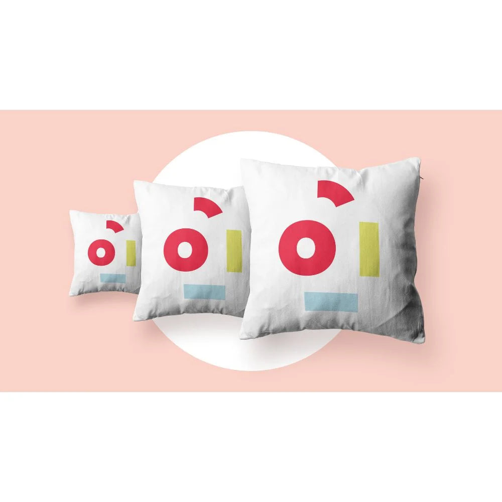 Three white cushions with colorful geometric prints made using the icolor 350 printer, staged on a soft pink background