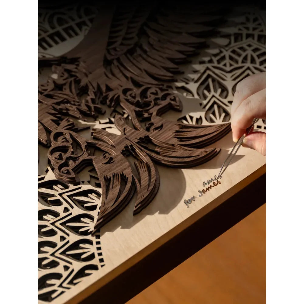 Hand removes tiny pieces from layered wood artwork cut with the xTool P3 during project finishing